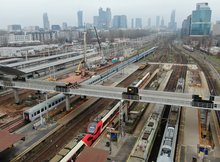 Widok z góry na kładkę nad peronami stacji. Pociągi na torach. W tle widok na centrum Warszawy_fot. Artur Lewandowski