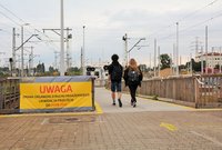 Baner zapowiadający zmiany w obsłudze podróznych na stacji Warszawa Zachodnia i ludzie podążający do tymczasowego przejścia, fot. Martyn Janduła