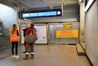 Baner informujący o zmianach w sposobie dojścia na perony. Podróżni w tunelu i informatorka PKP IC, fot. Martyn Janduła