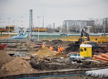 Widok na plac budowy na stacji Warszawa Zachodnia, pracownicy wykorzystują maszyny, w tle pociąg, fot. PLK