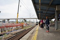 Podróżni na peronie oczekujący na wjeżdżający pociąg. Obok budowana płyta stropowa i kładka, fot. Martyn Janduła