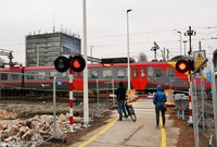 Pasażerowie czekający na podniesienie rogatek i przejeżdżający pociąg, fot. Martyn Janduła